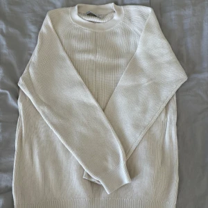 Beige stickad tröja från Zara - En stilren beige stickad tröja från Zara med rund halsringning och ribbade muddar. Tröjan har lång ärm och är perfekt för lager-på-lager under kyligare dagar. Enkel att matcha med både jeans och kjol för en clean look.