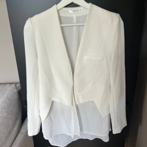 Vit kavaj cropped kavaj med detalj  - Säljer en vit kavaj med långa ärmar! Kavajen är sparsamt använd och fin med tygdetalj som faller ner. Köpt i en butik i Singapore. Köparen står för frakt 💕