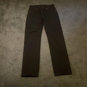 Svarta straight jeans från Wrangler - Säljer ett par svarta jeans från Wrangler med klassisk femficksdesign och raka ben. Byxorna har snygga nitar och läderpatch med Wrangler-logga på bakfickan. Perfekta för dig som gillar en clean och tidlös look.                                                                               W28/L32.     Knappt använd och har tyvärr inte kvitton med mig men köpte den i jeansbolaget. 