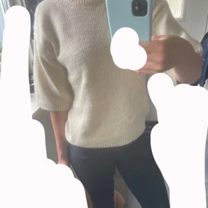 Beige stickad tröja från Stories - Superfin beige stickad tröja från Stories med korta ärmar och rund hals. Tröjan har en avslappnad passform och ribbade muddar vid ärmslut och nederkant. Köpt från Ullared.