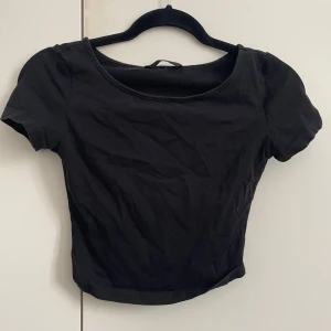 Svart croppad topp med kort ärm från Shein - En enkel svart croppad topp med rund halsringning och korta ärmar från Shein. Perfekt att matcha med jeans eller kjol för en clean look. Tunn och mjuk i materialet, sitter snyggt och figurnära.