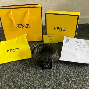 Fendi FF-logo bälte i skinn - Snyggt Fendi-bälte i svart och beige skinn med ikoniskt FF-mönster och matt svart spänne. Kommer med originalförpackning, dustbag och certifikat. Helt nytt, allt på bilderna följer med.