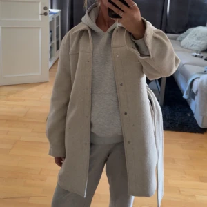 Beige kappa från Vero Moda - Säljer en beige kappa från Vero Moda med klassisk krage, knappar framtill och bälte i midjan. Perfekt till vår och höst!