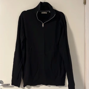Svart tröja med dragkedja  - Svart långärmad tröja från Jack & Jones med krage och dragkedja framtill. Tröjan har en stilren och enkel design, perfekt för en clean look. Materialet känns mjukt och följsamt.