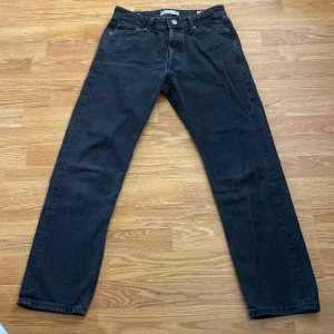 Svarta loose fit jeans från Jack & Jones - Säljer ett par svarta jeans från Jack & Jones i modellen Loose/Chris. Jeansen har klassisk femficksdesign och knappgylf. Storlek 28/30