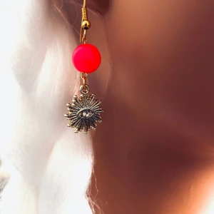 By prisförslag- 1 st Örhänge med rosa pärla och solöga - Unikt örhänge med en rosa sten pärla och ett hängande guldfärgat solöga med en gnistrande sten i mitten. Perfekt för dig som vill sticka ut med ett coolt och trendigt smycke.