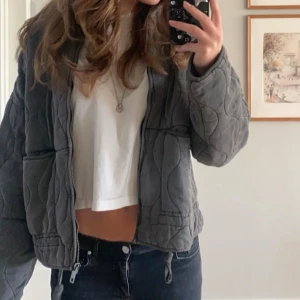 Grå quiltad jacka - Säljer en grå quiltad jacka med dragkedja och resår i midjan. Jackan har lång ärm och en avslappnad passform, perfekt för lager-på-lager. Snygg och enkel att matcha till olika outfits. Bara att skriva om du vill ha mer bilder🫶