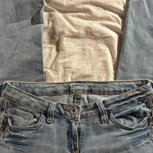 Ljusblå jeans - Lågmidjade utsvängda jeans Midjemått rakt över: 39cm Innerbenslängd: 84cm Som nya utom att de e lite slitna längst ner på ena benet (se sista bilden)