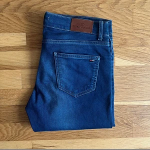  Tommy Hilfiger jeans-slim fit/stretch strl W33L34 - En mörkblå jeans från Tommy Helfiger exceptionellt bekväma stretchjeans med slim fit passform och en knappgylf.  - 57% Bomull 31% Polyster 2% Spandex