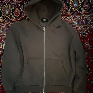 Brand of Roses boxy zip hoodie  - Säljer en mörkgrå hoodie från Brand of Roses i storlek L. Tröjan har dragkedja framtill, huva och två stora fickor. Perfekt för en avslappnad stil och enkel att matcha med det mesta. Boxy fit. 