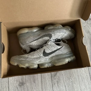 Nike Air Vapormax 2023 grå - Säljer mina vapormax då de är för små för mig, de är i gott skick allt ser bra ut förutom att det finns en skada typ ett hål i den högra skorn som man inte ser, de är rena och hela och billiga för sitt pris originalbox medföljer kan även frakta om det behövs och de är köpta för 3000 kr från Nike! Kontakta gärna ifall du har några frågor