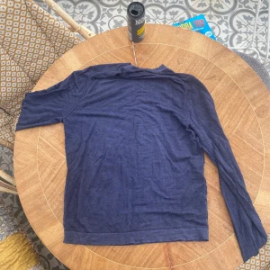 Blå merinoulltröja från Massimo Dutti - Säljer en tunn och mjuk långärmad tröja i blått från Massimo Dutti. Tillverkad i merinoull, perfekt för lager-på-lager och passar till många olika stilar. Klassisk och enkel design utan synliga detaljer.