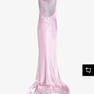 Ljusrosa balklänning från True Decadence - Säljer en elegant ljusrosa långklänning i satin med smala axelband och öppen rygg med knyt. Klänningen har en slits framtill och ett glansigt material som ger en lyxig känsla. Perfekt för bal eller festliga tillfällen. Endast använd en gång, då den är i nyskick💕