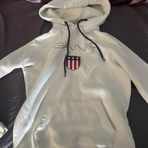 Vit hoodie från Gant - Vit hoodie Gant. Köpt på kidsbrandstore för många år sen. Storlek XS. Hade den när jag var kanske 150-160cm nånstans dör kommer ej ihåg. Skick 6/10 finns lite fläckar men kan nog gå att få bort ifall man har nåt bra medel.