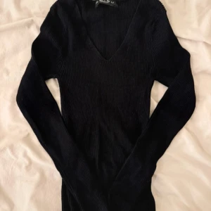 Svart ribbad långärmad tröja V-ringad - Säljer en svart ribbad långärmad tröja från Missguided. Tröjan har en snygg v-ringning och är figurnära med stretchigt material. Perfekt att styla med jeans eller kjol för en clean look.