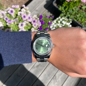 Oliv-Grön Seiko Mod Day-Date - Stilren Seiko klocka med oliv-grön urtavla, romerska siffror och dag/datumvisning. Inspererad av Day-Date. Boetten och länken är i blankt silverfärgat stål och urtavlan har en snygg solreflex. Perfekt accessoar för dig som vill sticka ut med en klassisk men modern look. Alla länkar + box tillkommer självklart vid köp‼️🙌 