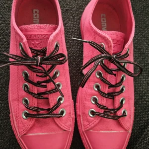 Rosa Converse All Star sneakers stl 37 - Säljer ett par rosa Converse All Star sneakers stl 37 med platåsula. Skorna har svartrosa snören och är tillverkade i canvas med gummidetaljer. Klassisk rund tå och lågt skaft, perfekta för dig som vill sticka ut med färg.