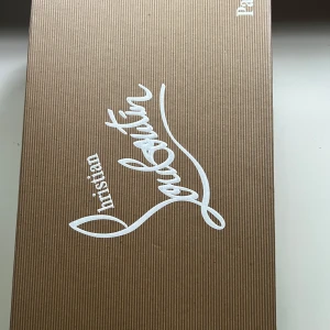 Mörkblå mocka sneakers från Louboutin - Snygga mörkblå sneakers från Christian Louboutin i lyxig mocka med ton-i-ton broderad logga på hälen. Skorna har svarta snören, rund tå och svart platt sula. Insidan är i ljust skinn med guldfärgad logga. Perfekta för dig som gillar exklusiv streetstyle. Helt nya 