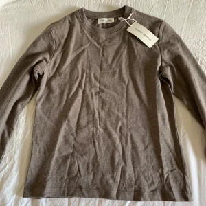 Brun långärmad tröja Carin Wester - En stilren brun långärmad tröja från Carin Wester i mjuk bomull. Tröjan har rund halsringning och en klassisk, rak passform som funkar till många olika looks. Perfekt basplagg för garderoben.