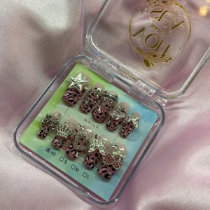 CherrySavage (XS);Medium Square - Set med y2k gelé press-on naglar i storlek XS: 14 mm, 11 mm, 11,5 mm, 10 mm, 8 mm,  med rosa bas/fade och svart leopardmönster. Naglarna är dekorerade med stora 3D-accessoarer i silver, som stjärna, rosett, krona, hjärta och körsbär. Perfekt för dig som vill sticka ut med coola detaljer och trendig design.