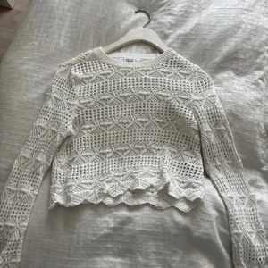 Vit tröja  - Superfin vit stickad tröja med långärmad design och snyggt hålmönster. Tröjan har en croppad passform och vågig nederkant som ger en trendig look. Perfekt att styla med jeans eller kjol. Vet inte vart den kommer ifrån så skriver de som står i den!