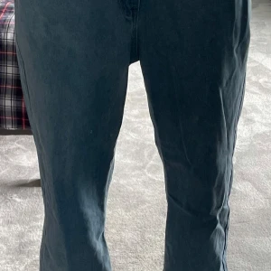 Blå raka jeans i bomull och polyester - Säljer ett par klassiska blå jeans med raka ben och normal passform. Byxorna har bakfickor och är tillverkade i en mix av 65% bomull och 35% polyester. Perfekta för dig som gillar en enkel och tidlös stil.