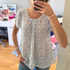 Blommig blus i blått och vitt - Supersöt blus med småblommigt blått mönster på vit botten. 