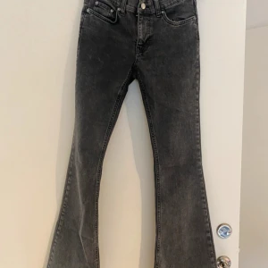 Svarta bootcut jeans med hög midja - Snygga svarta bootcut jeans med hög midja och klassisk femficksdesign. Jeansen har en lätt tvättad look och är tillverkade i ett stretchigt denimtyg som sitter skönt. Perfekta för dig som gillar en retroinspirerad stil med utsvängda ben.