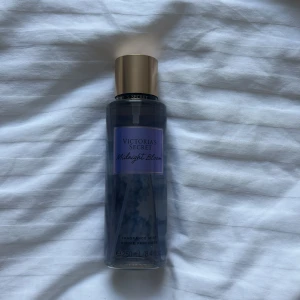 Victoria's Secret Midnight Bloom mist - Fräsch och blommig body mist från Victoria's Secret i doften Midnight Bloom. Flaskan är genomskinlig med lila etikett och guldigt lock. Innehåller 250 ml. Doftnoter av moon flower och creamy woods. Perfekt för dig som gillar mjuka och romantiska dofter.