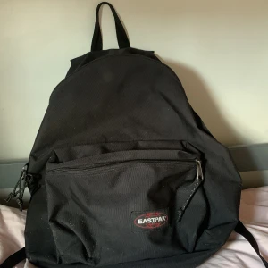 Eastpak ryggsäck - Klassisk svart ryggsäck från Eastpak med stort huvudfack och en praktisk ytterficka med dragkedja. Väskan har justerbara, vadderade axelremmar och är tillverkad i slitstark polyester. Perfekt för skola, jobb eller äventyr! Kontakta gärna om du har frågor eller prisförslag💛