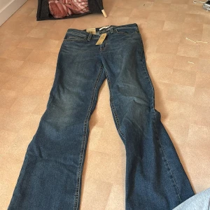 Levi's Superlow Bootcut jeans blå - Snygga blå Levi's Superlow Bootcut jeans med låg midja och klassisk bootcut-passform. Jeansen är i denim med fem fickor, orange sömmar och ikonisk Levi's-lapp bak. Perfekta för dig som gillar retrovibbar och en avslappnad stil.