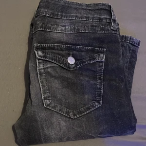 Svarta bootcut jeans med ficklock - Snygga svarta jeans från Gina tricot med bootcut passform. Jeansen har coola ficklock med knapp både fram och bak, samt tydliga sömmar som ger en tuff look. Materialet är klassisk jeans och färgen är tvättad svart med lite slitningar. Original pris:380kr säljer för: 200.