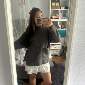 Grå stickad polotröja - Mysig grå stickad politröja med en lite oversized passform och lång ärm. Även så snygg med sina detaljer som den lilla fickan framtill och slitsarna i sidan! 