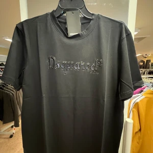 Svart Dsquared2 t-shirt med logga - Svart t-shirt från Dsquared2 med glansig 3D-logga framtill. Klassisk rund hals och korta ärmar. Tillverkad i mjuk bomull för en skön känsla och snygg passform. Perfekt för dig som gillar stilrena och trendiga plagg.