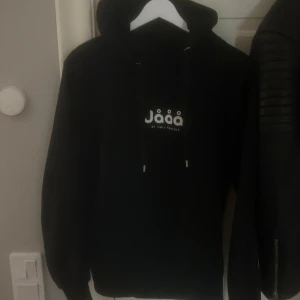  Jååå by Emil Hansius hoodie (går ej att köpa längre ) - Svart hoodie med vit Jååå-logga på bröstet och snörning i huvan. Klassisk passform med långa ärmar och ribbade muddar. Nypris 500kr men säljer för 350 då den ej går att köpa 