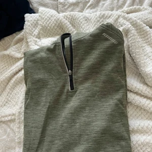 Grön half zip tröja från Karhu - Snygg grön tröja från Karhu med half zip-dragkedja framtill. 