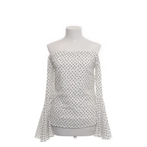 Vit offshoulder topp med prickar - Supersöt vit offshoulder topp med svarta prickar och vida trumpetärmar. Perfekt för dig som vill sticka ut med en romantisk vibe. Sitter snyggt över axlarna och har en figurnära passform. Köpt på sellpy💕