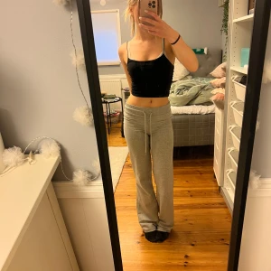 Svart croppad linnetopp - Säljer ett svart linne med tunna axelband från Gina tricot. Toppen har en enkel och stilren design som passar perfekt till jeans eller mjukisbyxor. Materialet känns mjukt och följsamt mot huden.