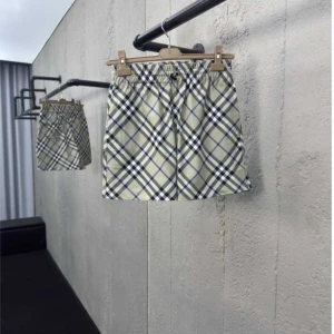 Beige rutiga shorts från Burberry - Snygga beige shorts från Burberry med klassiskt rutigt mönster i svart, vitt och blått. De har elastisk midja med snörning och en broderad detalj bak. Perfekta för sommaren och ger en clean, trendig look.