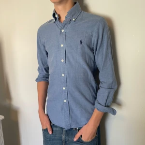 Ralph lauren skjorta  - Säljer denna riktigt snygga blåa Ralph lauren skjorta med mörkblått märke, den är i mycket bra skick, storlek S och modell slim fit den är 72 cm lång och 44 cm bred under armhålorna, hör gärna av dig vid frågor!