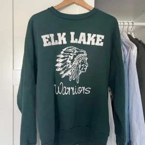 Mörkgrön sweatshirt med tryck - Säljer en mörkgrön sweatshirt med vitt tryck på bröstet, snygg färg och skön sweatshirt. Köpt i en vintage butik i Hamburg förra året.