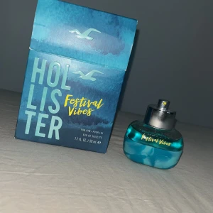 Festival Vibes parfym från Hollister - Fräsch parfym från Hollister, Festival Vibes. Kommer i en blå glasflaska med silverfärgad spraykork och tillhörande blå kartong. Flaskan rymmer 50 ml och har en modern, ungdomlig design med turkosa och gula detaljer. Är Använd och har inte locket för den.
