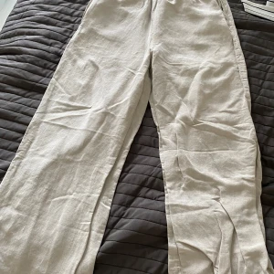 Beige linnebyxor från H&M - Snygga och luftiga beige linnebyxor från H&M med resår i midjan. Perfekta för varma dagar och har en avslappnad passform med raka, vida ben. Gjorda i en linneblandning som känns sval och skön mot huden.