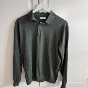 Grön stickad pikétröja från Mango man - Säljer en stilren grön stickad pikétröja från Mangons. Tröjan har klassisk krage, knäppning med två knappar och långa ärmar. Perfekt för en avslappnad men ändå uppklädd look.