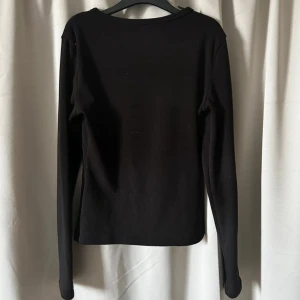2-pack långärmade tröjor i svart och vit - Säljer två basic långärmade tröjor i svart och vit. Båda har rund hals och är gjorda i mjuk bomull med borstad insida för extra komfort. Perfekta att ha som lager under jacka eller hoodie.