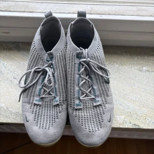 Grå Nike vapormaxes - Säljer ett par grå Nike vapor maxes med snörning. Skorna har en bubbel sula samt diskreta Nike-loggor framtill. Bubblorna är i bra form och har luft i sig. Pris kan diskuteras!