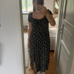 Svart blommig långklänning med puffärm - Säljer en svart långklänning med små vit/rosa blommor och korta puffärmar. Klänningen har en lätt rynkad byst och rundad halsringning. Perfekt för sommarens alla tillfällen! Tveka inte att höra av dig vid intresse eller någon fråga!💞💞