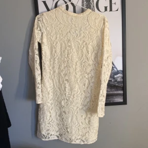 Vit spetsklänning  - Säljer en vit spetsklänning från Bik Bok i storlek XS. Klänningen har lång ärm, är täckt med spets och har pärldetaljer. Perfekt för dig som gillar romantisk stil och vill sticka ut med fina detaljer.
