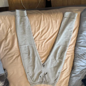 Grå mjukisbyxor från Zara - Säljer ett par ljusgrå mjukisbyxor från Zara med resår i midjan och benslut samt dragsko. Perfekta för en avslappnad stil och riktigt sköna att ha på sig.