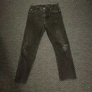 Svarta jeans från Armani Jeans - Säljer ett par svarta jeans från Armani Jeans med klassisk femficksdesign och raka ben. Jeansen har silverfärgade knappar och detaljer samt AJ-logga på bakfickan. Materialet är bomull med lite stretch för extra komfort.